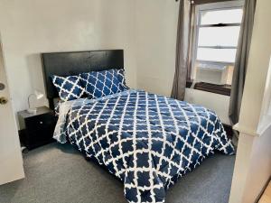 大西洋城3 Bedrooms, Boardwalk Duplex Beachblock Home!的一张带蓝色和白色棉被的床和一个窗口