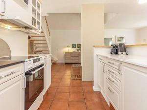 布拉万德6 person holiday home in Bl vand的厨房配有白色橱柜和瓷砖地板。