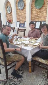 希瓦Khiva Ibrohim Guest House的一群坐在餐桌上吃食物的人