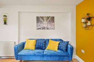 KentSleeps 5 - Large Garden - Wifi的客厅配有蓝色沙发及黄色枕头