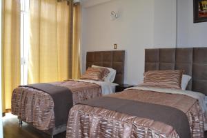 塔克纳Departamentos Amoblados Tacna Heroica的两张睡床彼此相邻,位于一个房间里