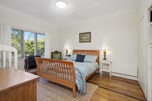 Mount WilsonGowan Ross Cottage的一间卧室配有一张床、一张书桌和窗户。