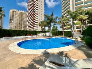 卡尔佩Esmeralda Suites 21º piso的一座棕榈树和建筑的大型游泳池