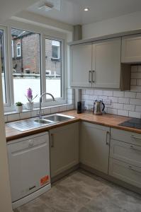 利物浦Library House的厨房配有白色橱柜、水槽和窗户。