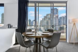 悉尼Broad Land Premium Apartments Chatswood Sydney的一间带桌椅和大窗户的用餐室