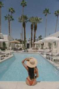 棕榈泉Yara Hotel - Adults Only的坐在游泳池前戴帽子的女人