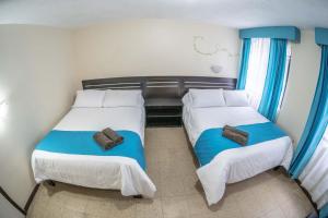 巴尼奥斯Hotel Tungurahua的小房间设有两张床,配有蓝色窗帘