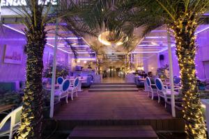 胡志明市A&EM潘伯舟路酒店的餐厅拥有棕榈树和白色的椅子及灯