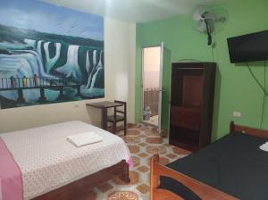 廷戈玛丽亚HOSPEDAJE EL CANTARO的卧室配有一张床,墙上挂有绘画作品
