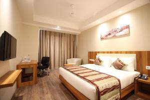 赖布尔Hotel Le Roi Raipur at Raipur Railway Station的酒店客房配有一张床、一张书桌和一台电视。