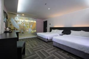 北赖S Hotel Seberang Jaya的酒店客房设有两张床,墙上挂有绘画作品