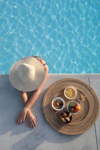 纳克索斯岛卡斯特拉基Irida Vacation suites的坐在游泳池旁的戴帽子的女人