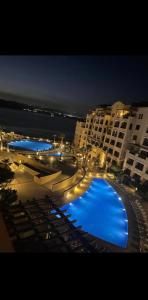 索瓦马Apartment at Samarah Dead Sea Resort的一个带休息室和遮阳伞的大型游泳池(晚上)