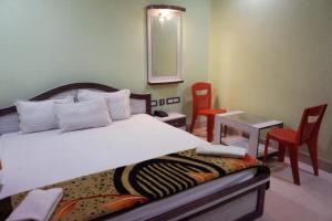 迪卡Goroomgo Muskan Guest House Digha的卧室配有一张床和一张桌子及椅子