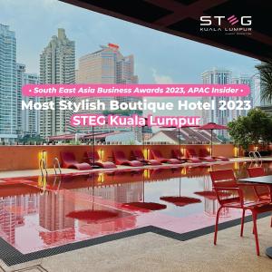 吉隆坡STEG Kuala Lumpur的酒店设有带红色椅子的游泳池和大楼