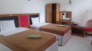 武吉丁宜Hotel Asia Bukittinggi的酒店客房,设有两张床和镜子