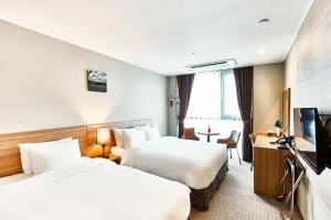 平泽市The Interra Hotel Pyeongtaek的酒店客房设有两张床和一台平面电视。