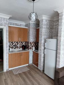 安塔利亚Konyaaltı Tunç Apart的厨房配有木制橱柜和白色冰箱。