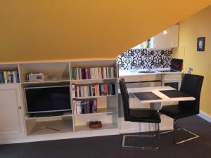 巴德贝芬森Appartementhaus Grieger的客房设有书桌、电视、桌子和椅子。