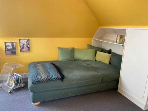 巴德贝芬森Appartementhaus Grieger的一张位于带绿色沙发的房间内的床铺