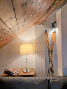 安锡Chalet charm in the heart of the old town - 40m2的一张桌子,桌子上放着一盏灯,滑雪板靠在墙上