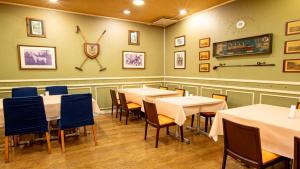 小牧市小牧シティホテル的一间设有桌椅的用餐室和墙上的时钟