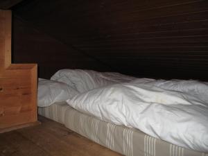 特林斯Chalet Hüttl by Interhome的一张带白色床单和木制橱柜的未铺好的床