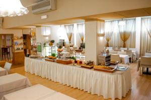 米兰eco Hotel Milano & BioRiso Restaurant的餐厅提供自助餐,配有白色的桌椅