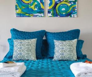 史密斯海滩1-bedroom unit with balcony and ocean views!的蓝色沙发,带两个枕头和两幅画