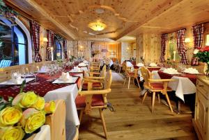 霍赫克尼希山麓丁滕米特尔维尔特康体酒店的餐厅设有桌椅和黄色玫瑰