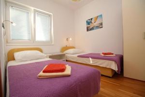 希洛Apartmani Zec的客房设有两张带紫色床单的床和窗户。