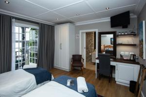 金伯利Milner House Kimberley的酒店客房配有两张床和一张书桌