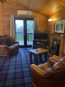 罗厄德南Cozy Cabin with Stunning Loch Lomond Views的带沙发、电视和桌子的客厅