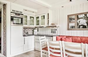 法尔松Farsund Resort的厨房配有白色橱柜和红色椅子