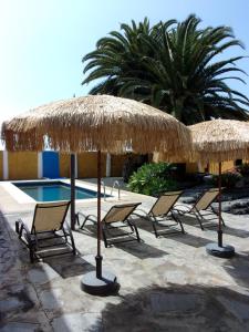 埃尔帕索Apartamentos Casa Rosán, junto a la Caldera de Taburiente的一组椅子和遮阳伞,位于游泳池旁