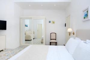 卡普里塞莱尼酒店的白色卧室设有一张大床和镜子