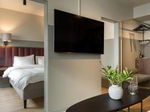 韦克舍韦克舍城镇精英酒店的一间卧室配有一张床,墙上配有电视