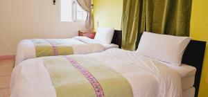 长滨乡小阿姨野花的配有白色床单的酒店客房内的两张床