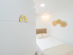 托雷德本纳贾尔邦Cubo's Hostal William's Sunny 5 with Breakfast的白色卧室,墙上挂着一顶床和帽子