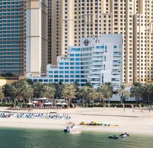 迪拜喜来登朱美拉海滩度假酒店的享有海滩美景,海滩上种植了建筑和棕榈树