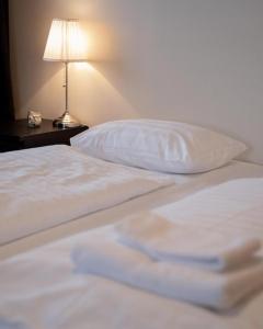 FlateyriFisherman Guesthouse Flateyri的一张带白色床单、枕头和灯的床