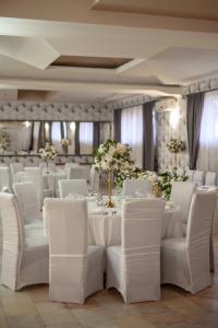 巴亚马雷Hotel IMPERYUM的宴会厅配有白色的桌椅和鲜花