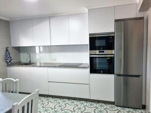 维戈Casa Alcabre (Samil)的厨房配有白色橱柜和不锈钢冰箱