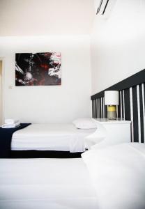 拉纳卡Olive Island的白色的客房配有两张床和一盏灯