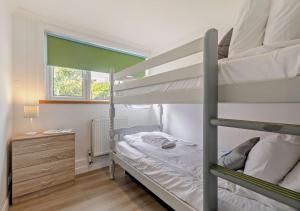 Saint LevanThe Beach House - Porthcurno的一间卧室设有两张双层床和一扇窗户。