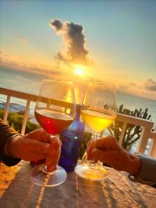 特罗佩阿Mediterranean Boutique Hotel的两人在餐桌上拿着酒杯,日落