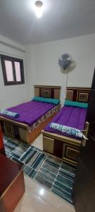 Qaryat Shurūqشاليه للايجار بقرية جراند هيلز الساحل الشمالى ٣ غرف بإطلاله مباشره على البول的紫色床垫间内的两张床