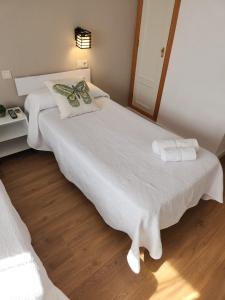 La PueblanuevaHostal Restaurante CASA FRAN的一间卧室配有两张带白色床单和镜子的床