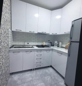 博尔若米White House In Borjomi的厨房配有白色橱柜、水槽和冰箱。