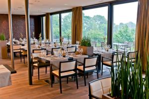 利普斯维尔高尔夫全景疗养酒店的餐厅设有桌椅和大窗户。